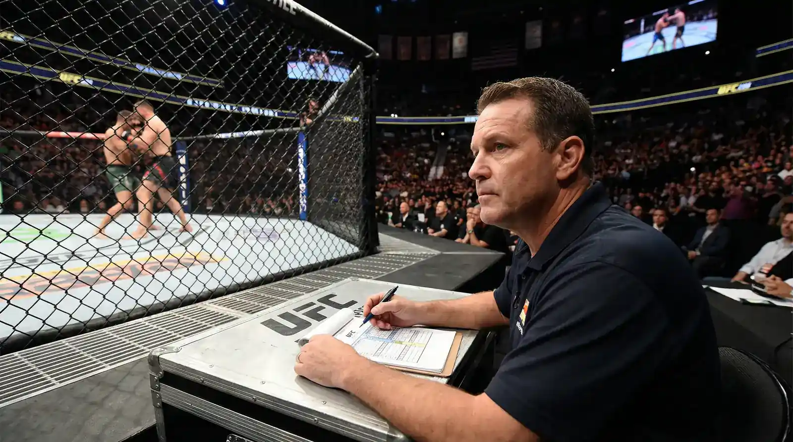 Sedzia przy oktagonie UFC oceniajacy runde walki z karta punktowa w dloni